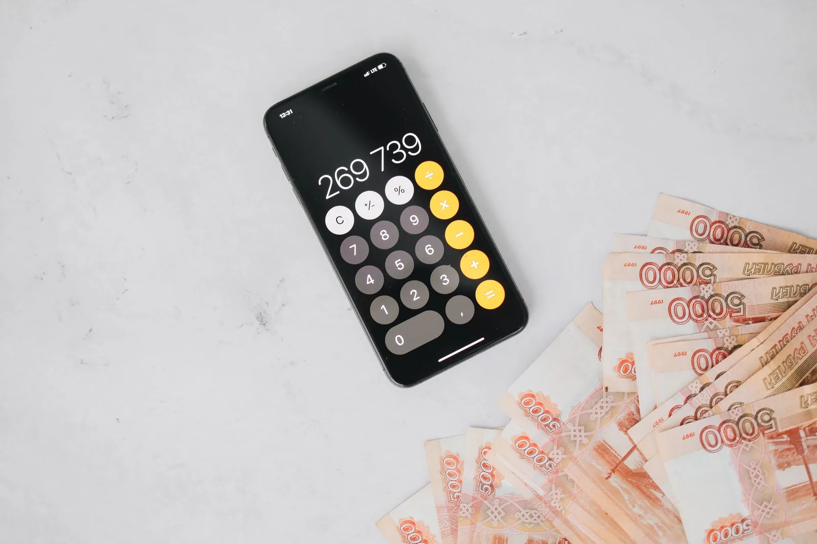Smartphone com cálculo financeiro sobre superfície de mármore, ideal para produtos digitais de loterias